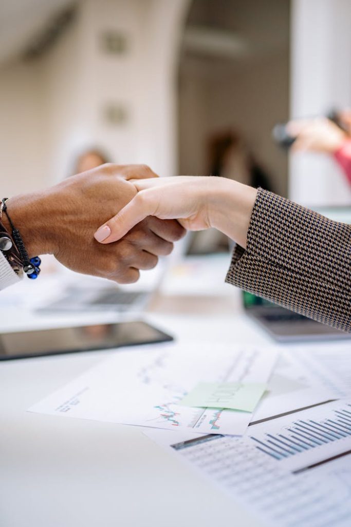 Close-up of a professional handshake over business documents, symbolizing partnership and agreement.