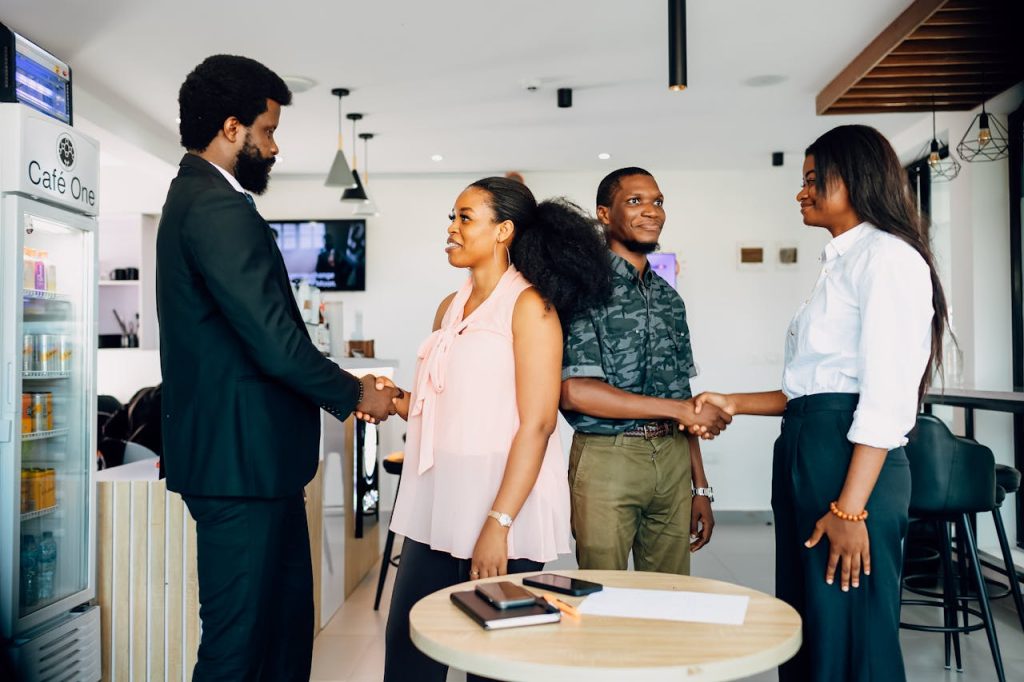 Business meeting with handshake in a modern Lagos cafe, showcasing collaboration and teamwork.